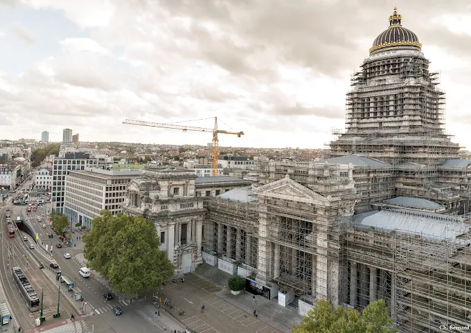 Le Palais de justice de Bruxelles sous échafaudages, vu depuis les hauteurs, avec le boulevard et les trams en contrebas.